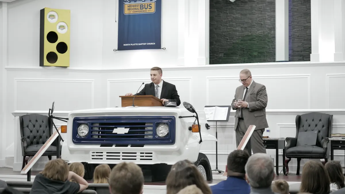 A preacher at the pulpit built from the front of a white bus