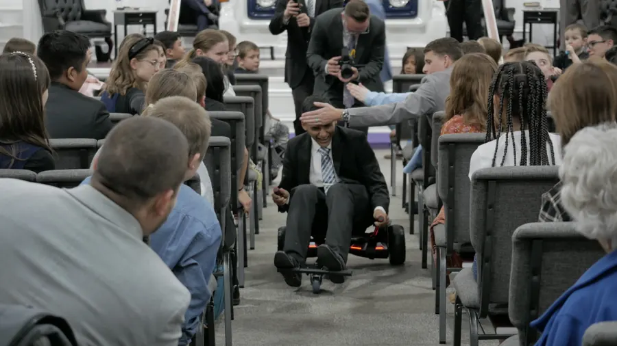 A man racing a small cart down the aisle while the crowd cheers