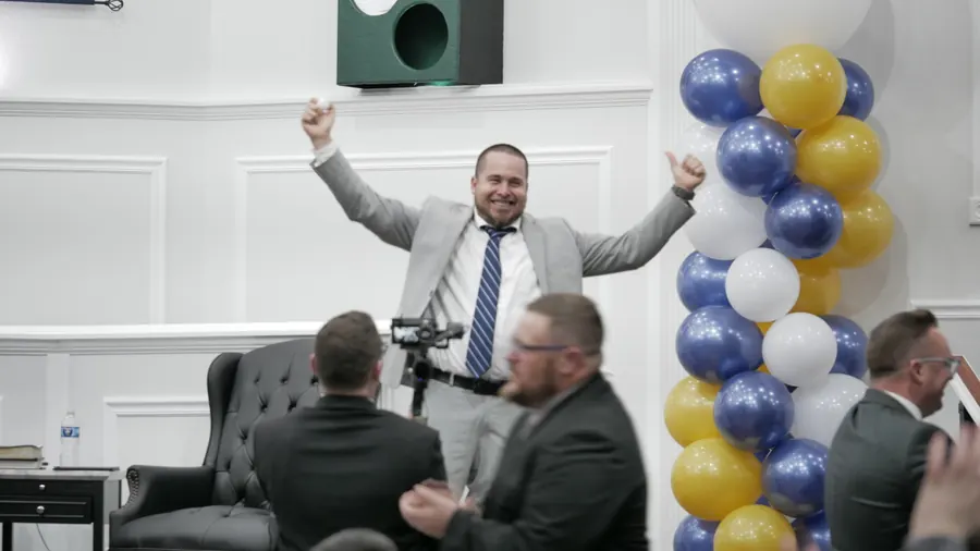 A man throwing his arms up to celebrate on stage