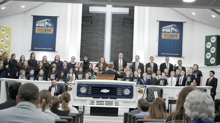 The children’s choir singing behind the pulpit built from the front of a bus