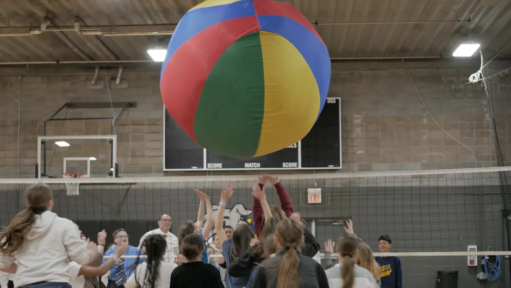 Teens batting a giant beach ball in the gym